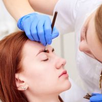 Young woman on eyebrow correction in cosmetology clinic.